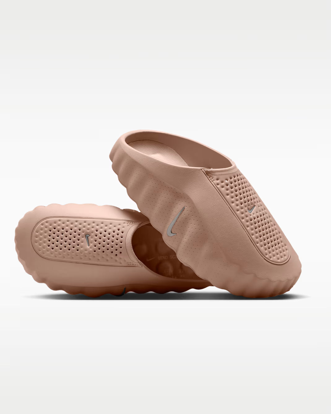 A pair of Nike slip-on clogs in a dusty rose pink color, displayed against a clean white background.