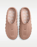 A pair of Nike Mule sneakers shown from a top-down view, featuring a dusty rose pink color with textured, perforated uppers and thick, wavy soles.