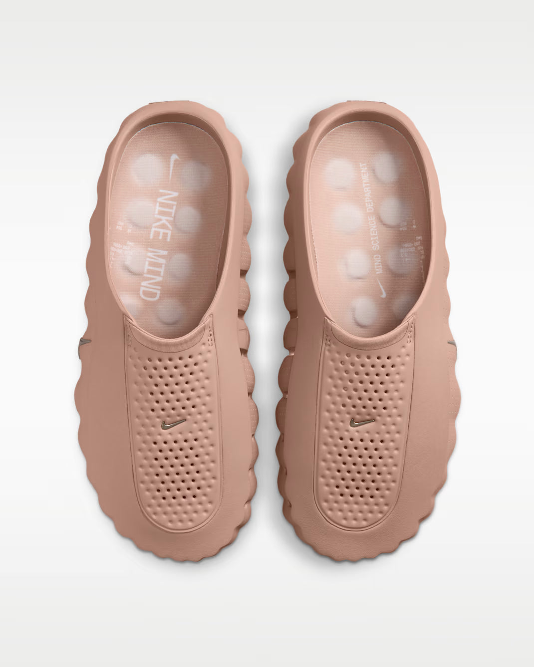 A pair of Nike Mule sneakers shown from a top-down view, featuring a dusty rose pink color with textured, perforated uppers and thick, wavy soles.