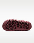 The textured outsole of a Nike shoe in a deep burgundy color, featuring rows of circular raised nubs and a small embossed Swoosh logo, shown against a light gray background.