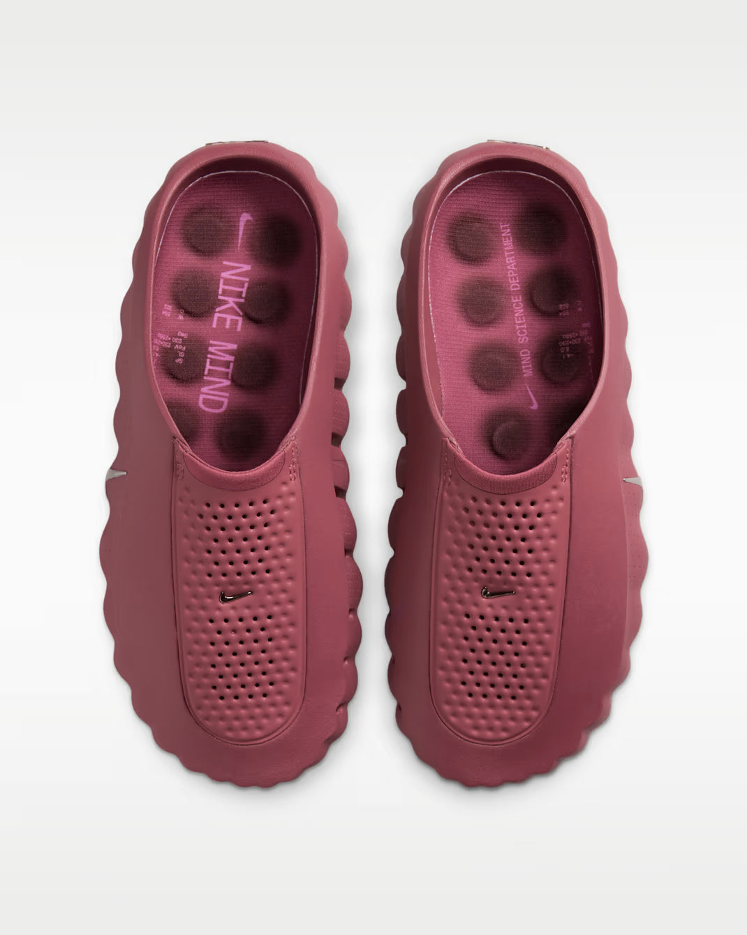 Pair of pink clogs with Nike branding on a white background